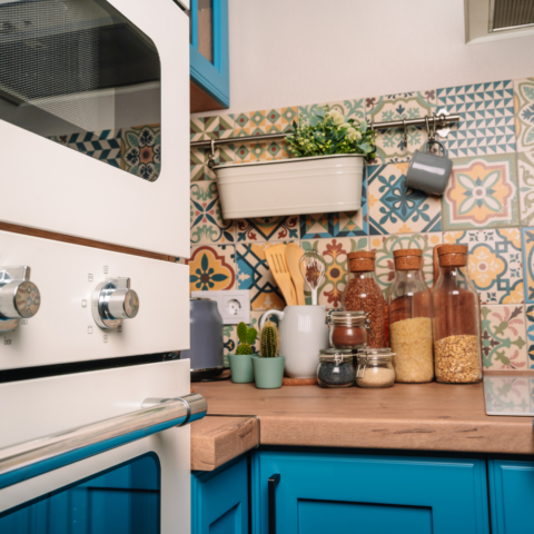 colorful backsplash tiling on top of bright blue cabinets with natural wood countertops